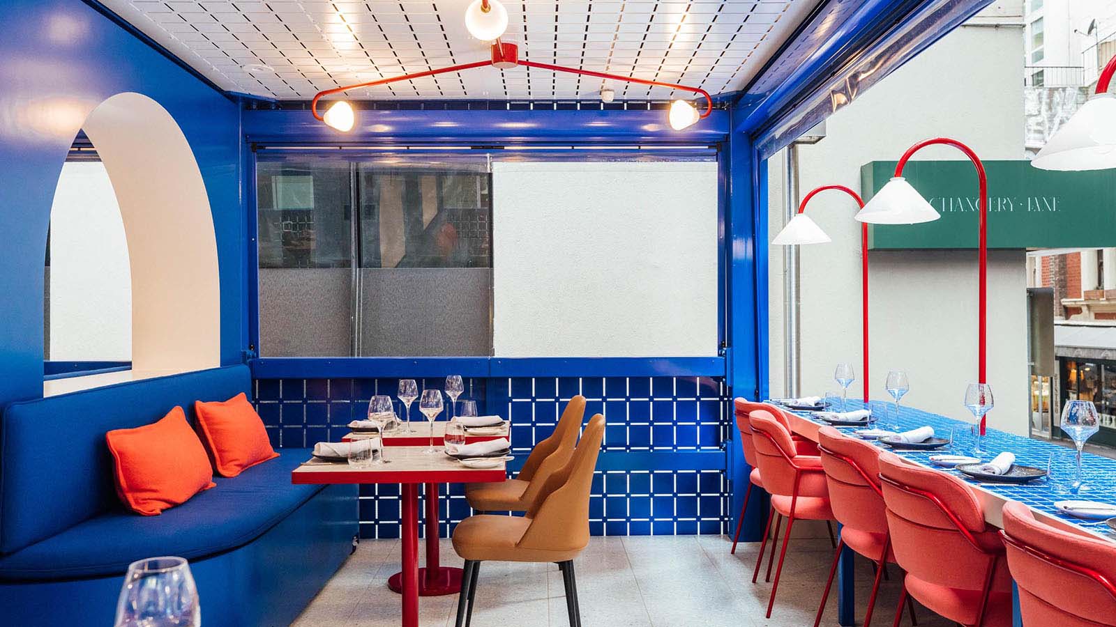 The inside of Sojourn, with blue, tiled walls and bright red chairs.
