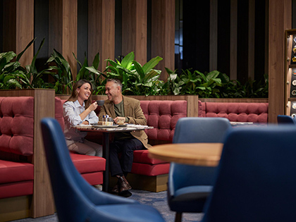 A couple enjoying a meal in a red booth in the RACV City Club lounge.