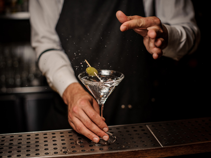 Bartender making a fresh and strong summer martini cocktail with olive and salt