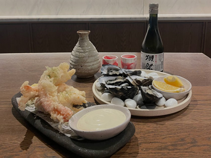 A Japanese inspired seafood meal with a bottle of Saki. 