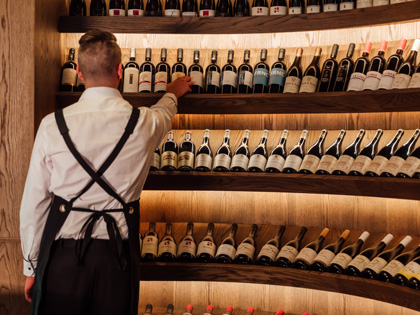 Waiter selting some wine from an expansive collection.