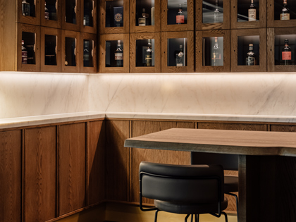 Numerous bottles of whiskey  locked away and showcased in wooden and glass display lockers. 