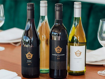 Two bottles of red and two bttles of white RACV branded wine placed on a set table.