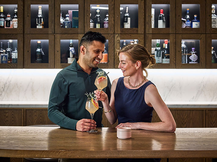 Couple smiling and toasting drinks at RACV City Club's wine bar.