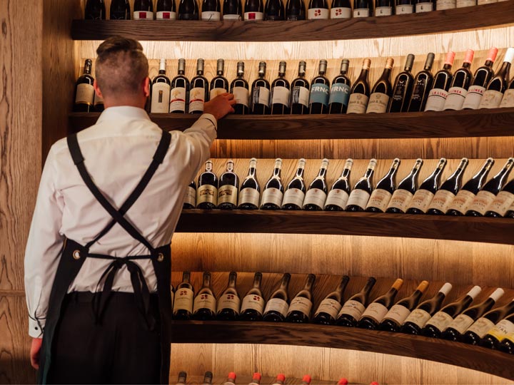 A waitign reaching for a bottle of line from a large selection.