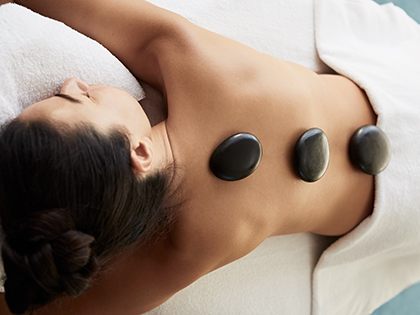 Woman lying down with hot stones on her back at RACV One Spa.