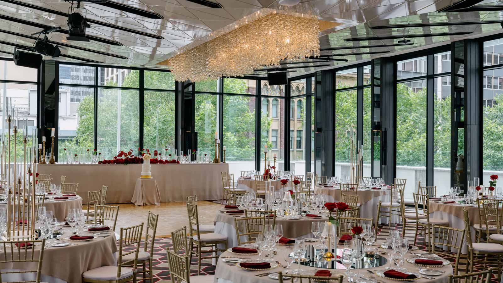 Full view of the Club Pavilion with floor to ceiling windows, bridal table, dance floor and tables
