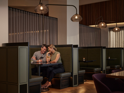 A couple dining in a booth with some wine.
