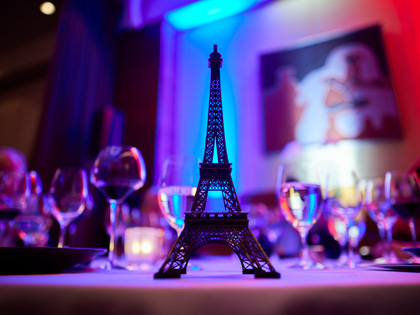 An eiffel tower statue sitting on a table filled with glasses of wine.