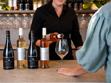 A bar tender pouring wine from a selection lined up. 