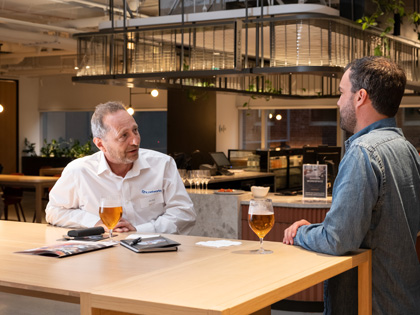 Two people enjoying a glass of beer and chatting to eachother. 