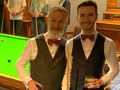 Two people dressed up having a drink in the billiards room 