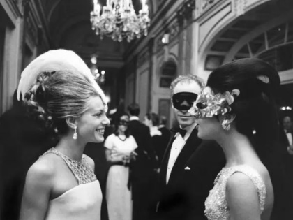 Old black and white photo of two women at a ball wearing masks