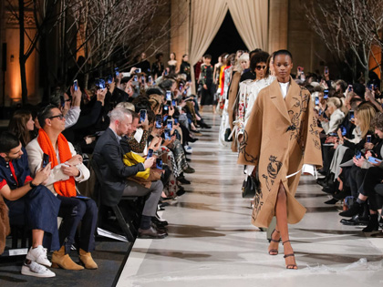Models walking a catwalk with onlookers. 