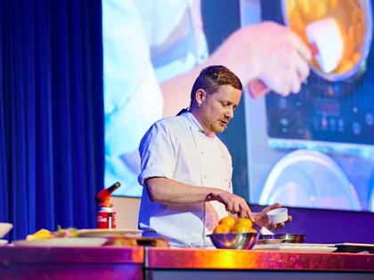 A chef cooking on stage. 
