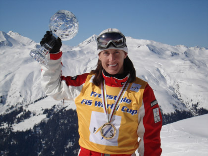 A woman standing on a snowy mountain holding a trophy. 
