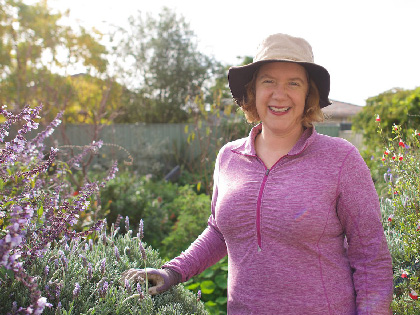 A woman smiling standing next to a lavender bush