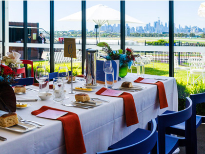 Table set for a lunch overlooking the racing track with a city skyline. 