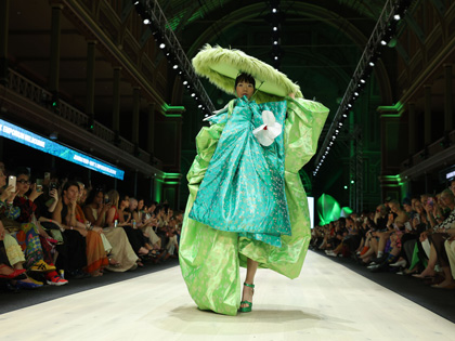 A woman on the runway wearing some bright green material.
