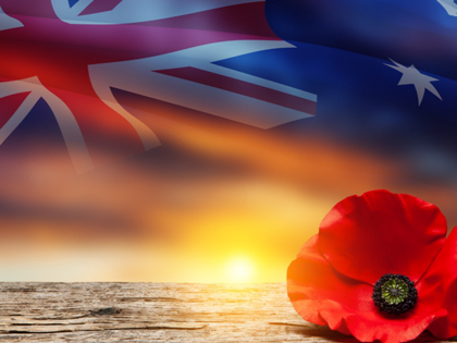 A poppy and Australian flag with a sunset in the background