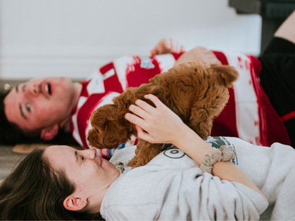 Two people doing yoga with a puppy. 