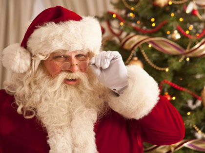 Santa holding his glasses and smiling. 