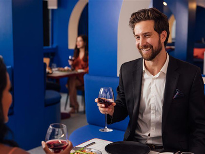 A smiling man with a glass of red in Sojourn.