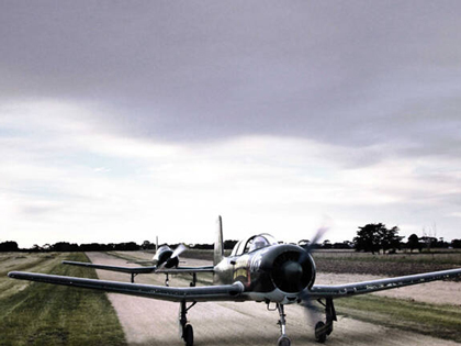 Two warbird planes on the tarmac.