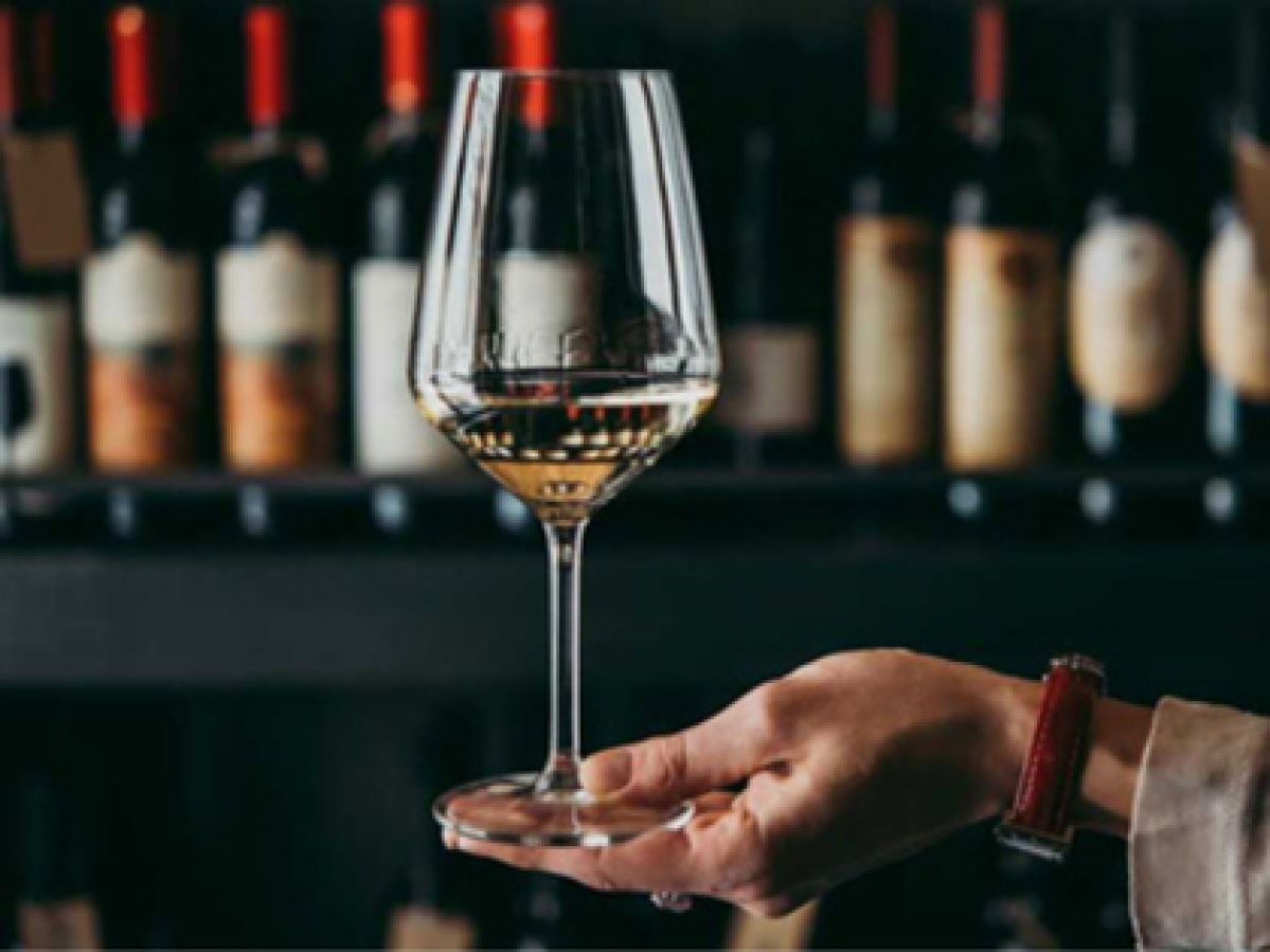 A hand holding a glass of white wine