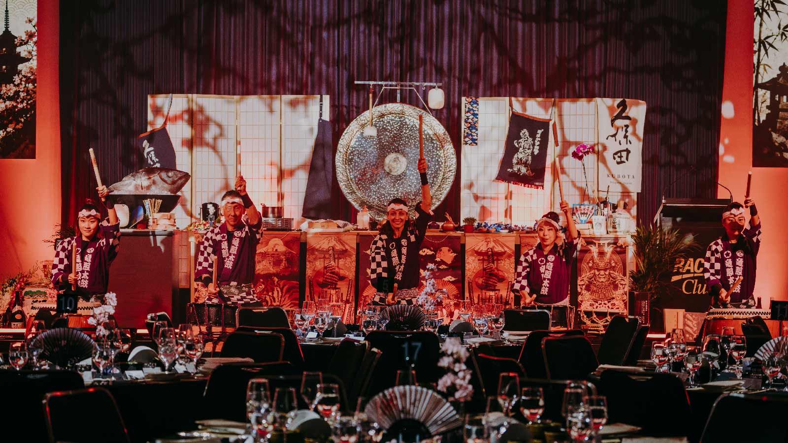 Japanes performers on stage playing traditional drums.