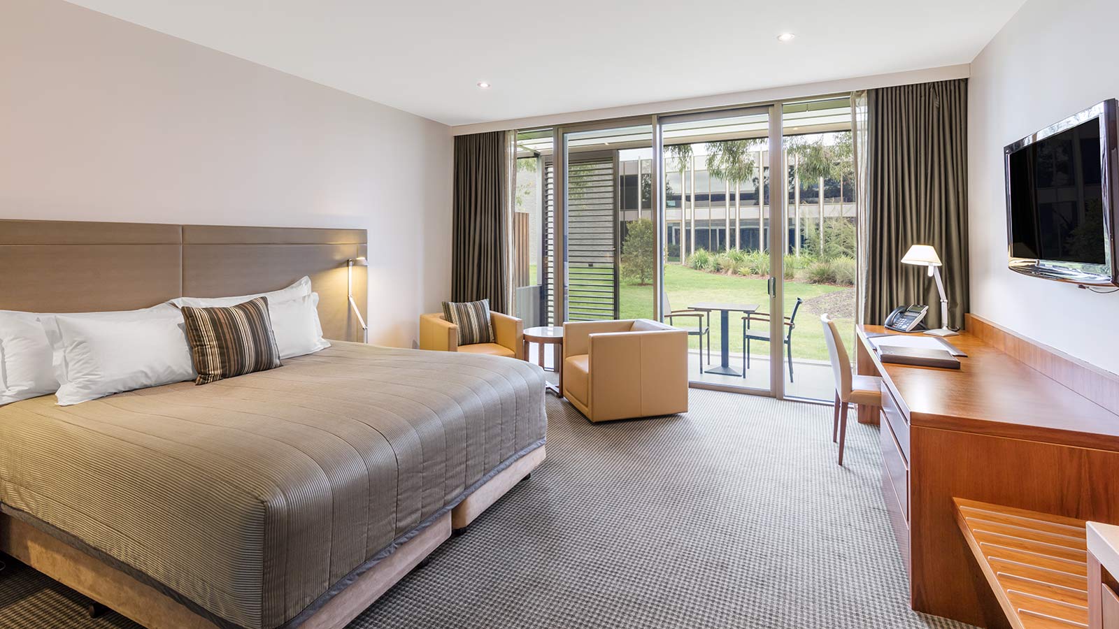 Lawn View Room at RACV Healesville Country Club and Resort, featuring a king bed, desk, TV, couches and outdoor seating area with views of the lawn.