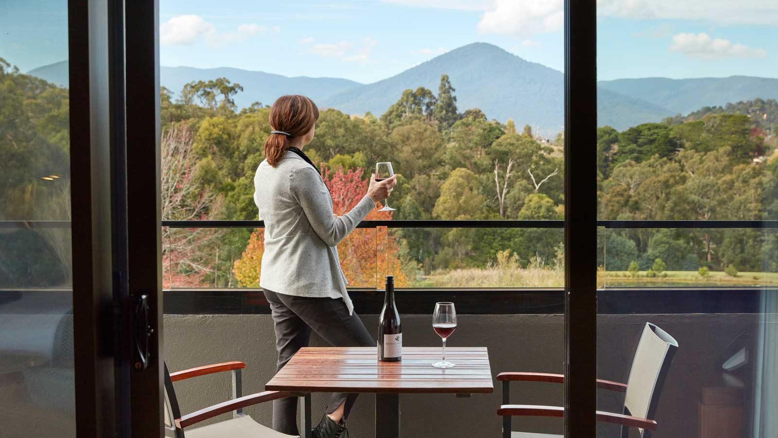 A woman enjoying a glass of wine with the view from the balcony.