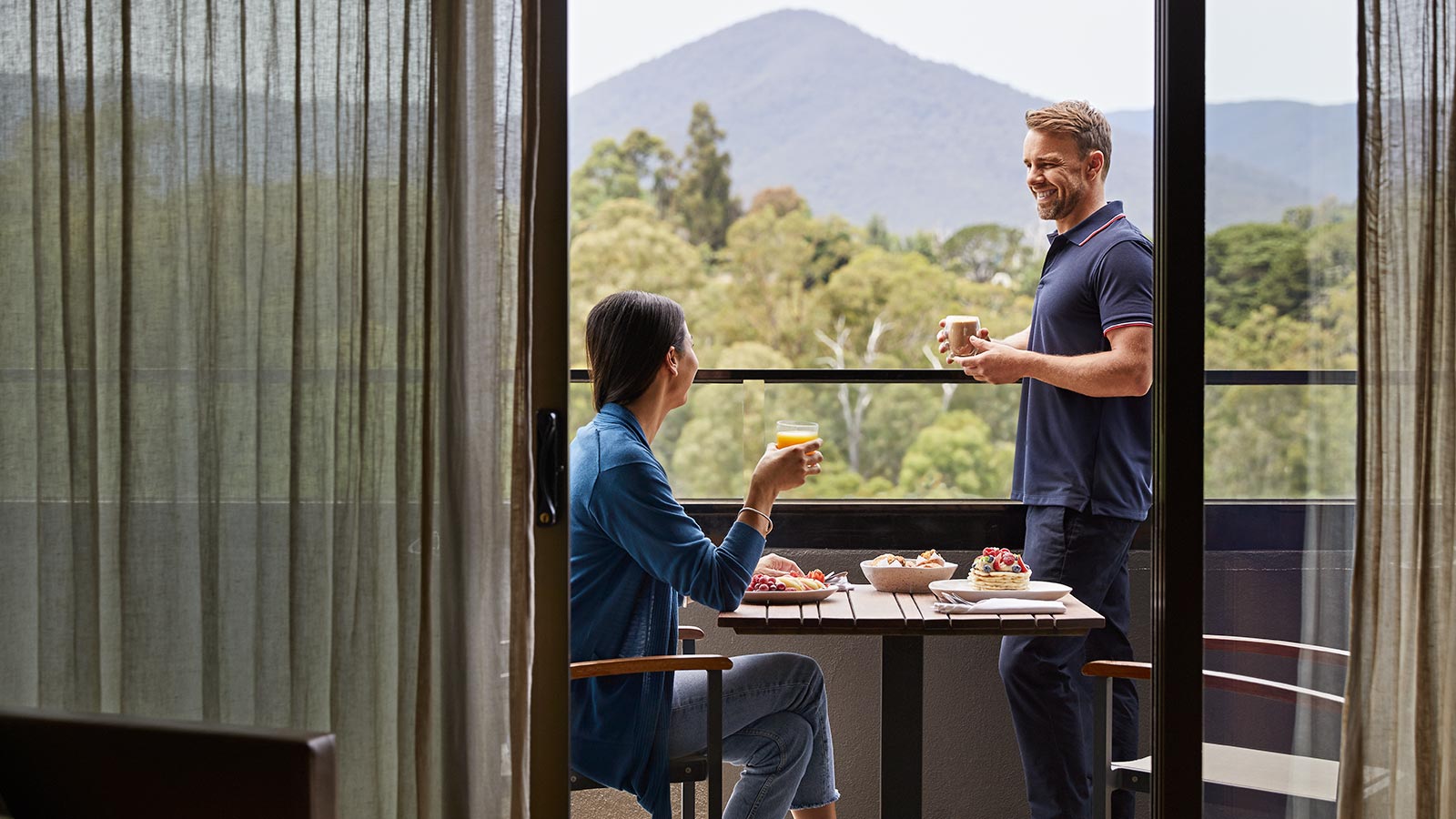 A couple enjoying breakfast on the balcony of their room at RACV Healesville Country Club and Resort.