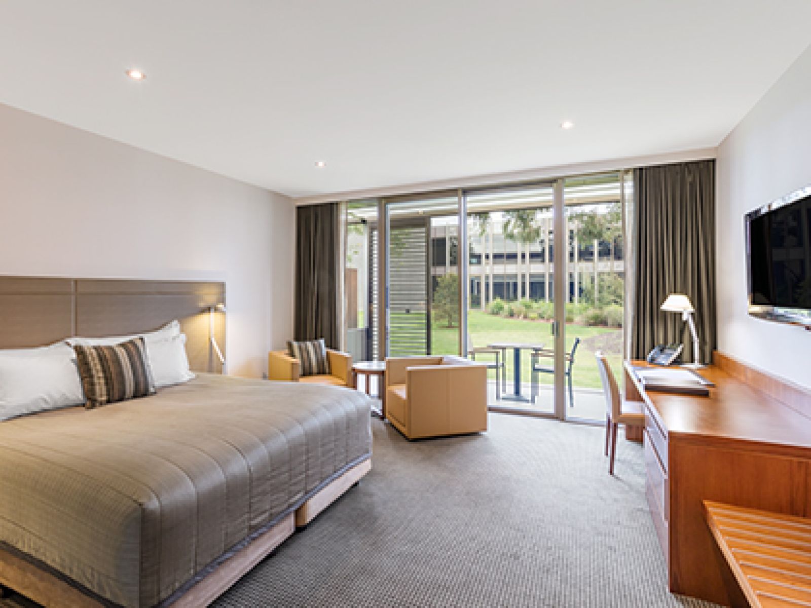Lawn View Room at RACV Healesville Country Club and Resort, featuring a king bed, desk, TV, couches and outdoor seating area with views of the lawn.