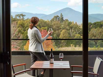 A woman enjoying a glass of wine with the view from the balcony.