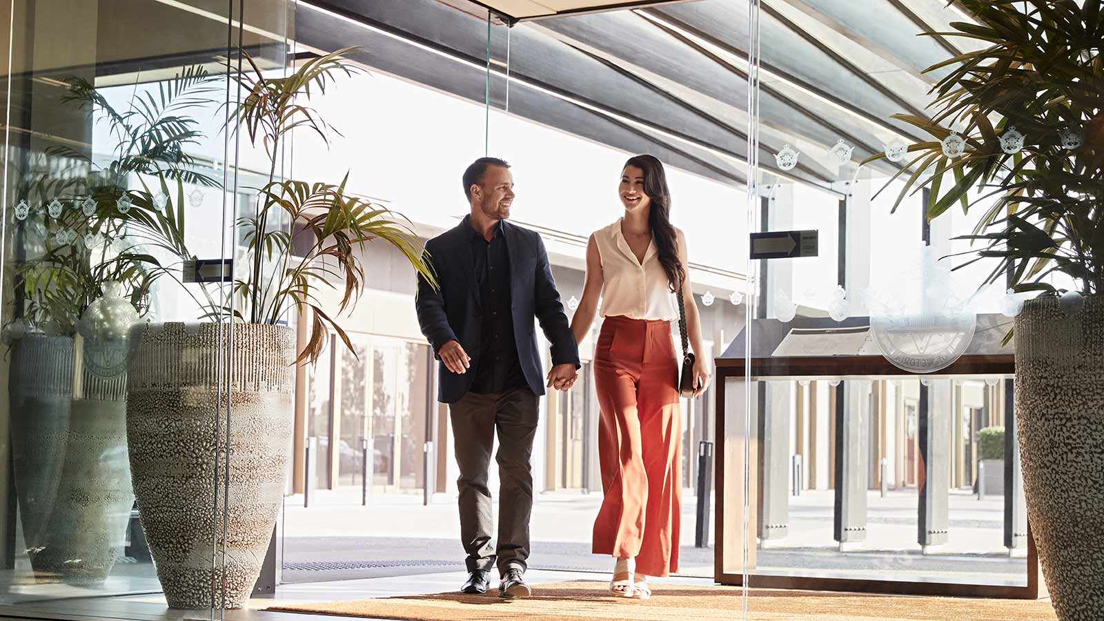 Two people holding hands and walking inside RACV Healesville Country Club and Resort.