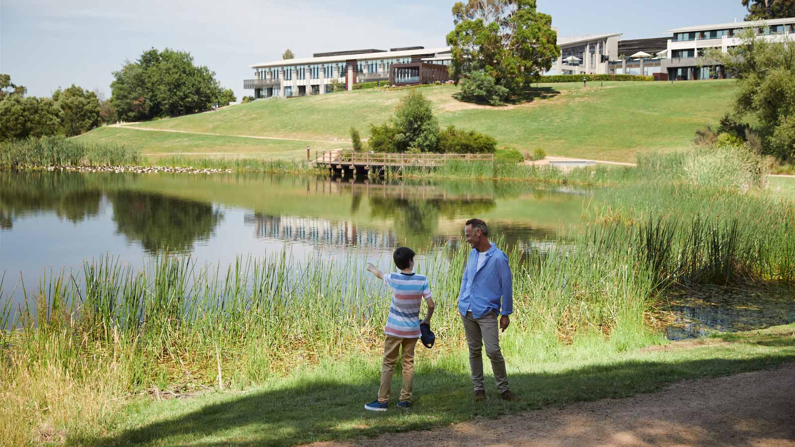 Adult and child looking and standing by lake at RACV Healesville Country Club and Resort.