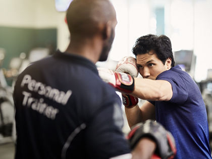 A person boxing with a trainer. 