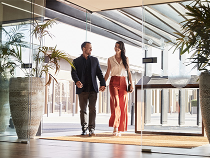 Two people holding hands and walking inside RACV Healesville Country Club and Resort.