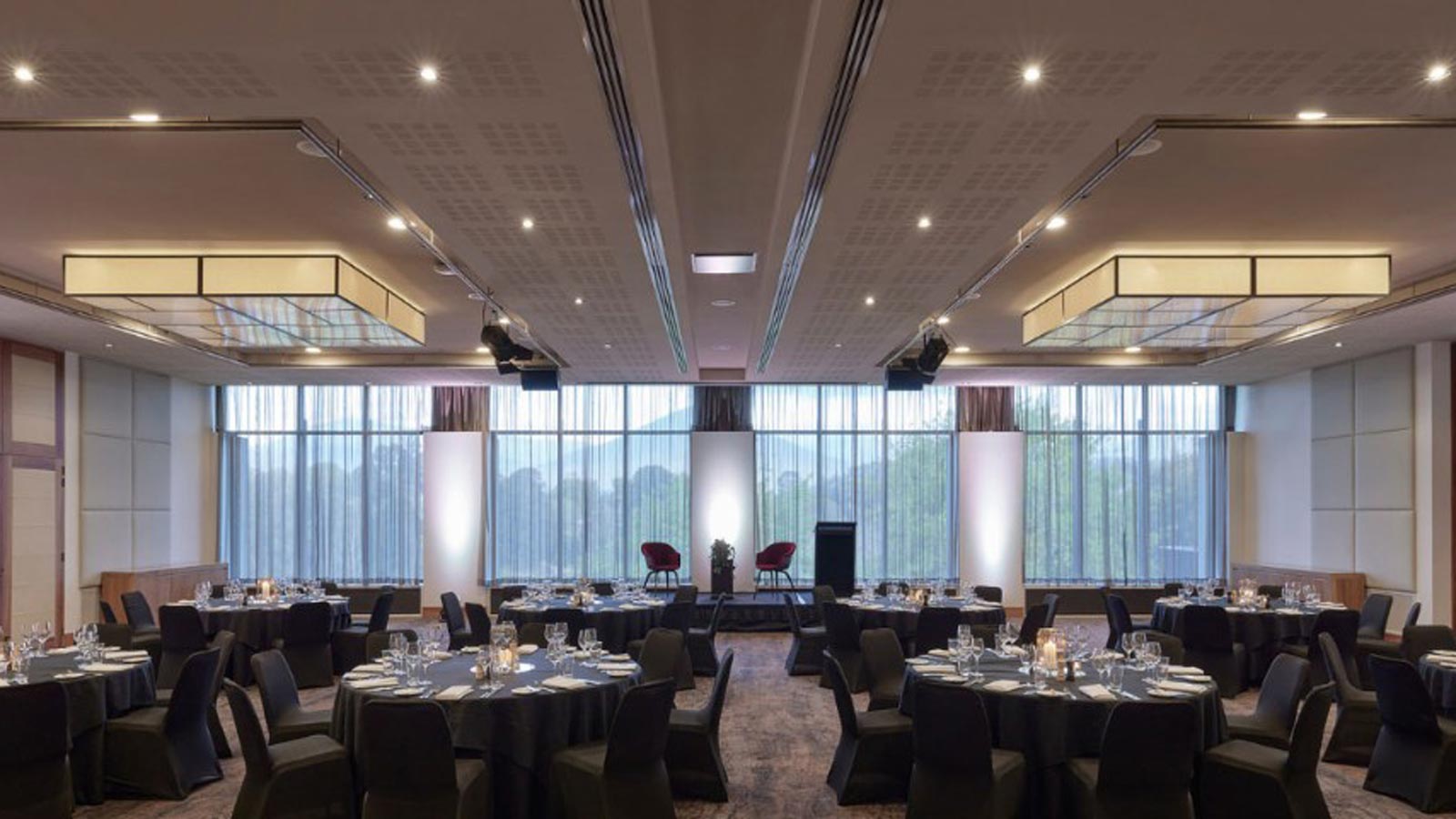 Ballroom decorated with black tables and chairs banquet style.