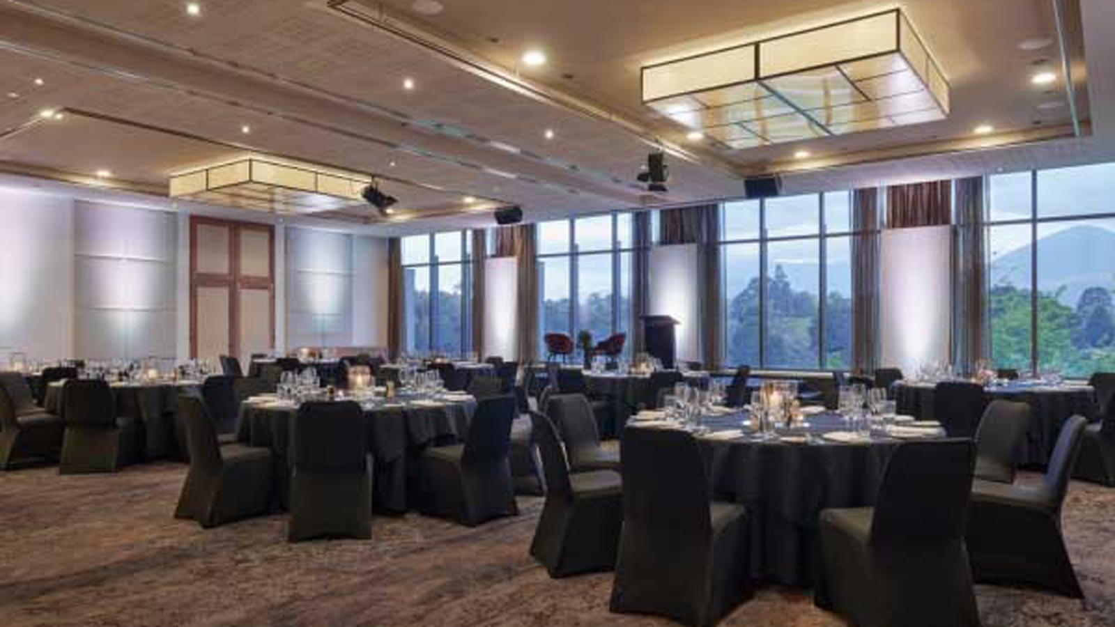 Ballroom decorated with black tables and chairs banquet style.