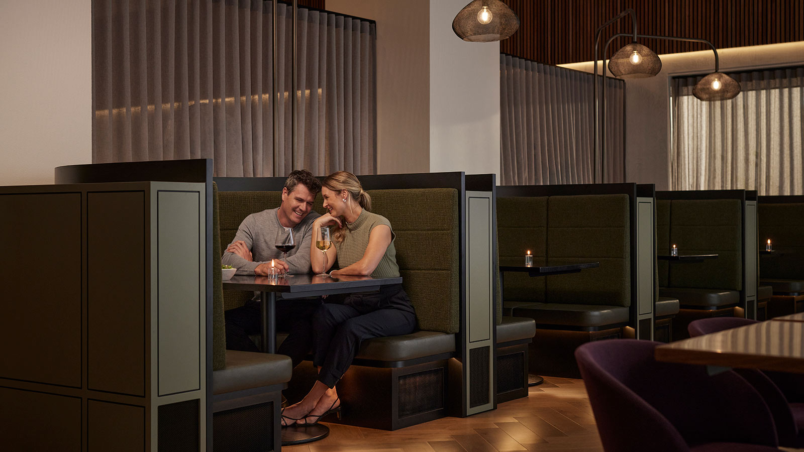 Two people sitting in a booth and drinking wine together at Banyalla, RACV Healesville Country Club and Resort.