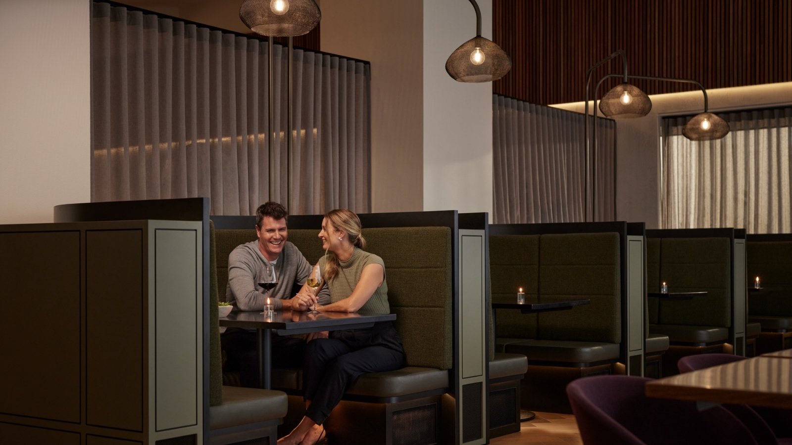 Two people sitting in a booth and drinking wine together at Banyalla, RACV Healesville Country Club and Resort.