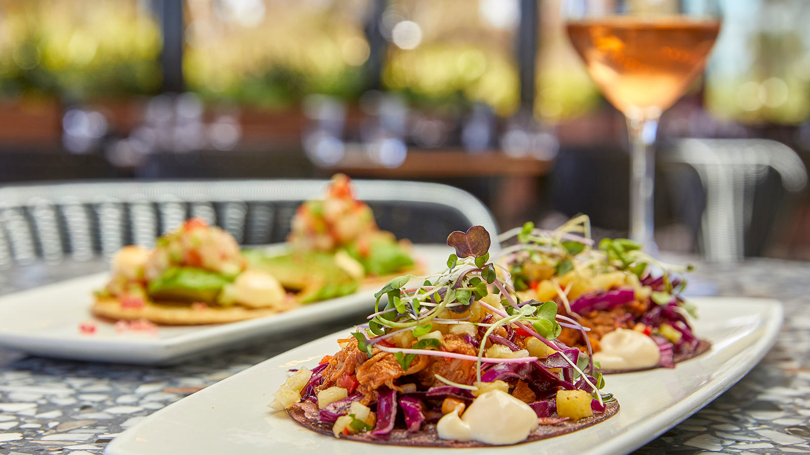 A glass of wine and two platters with chicken tacos at RACV Healesville's Riddell's Green restaurant.