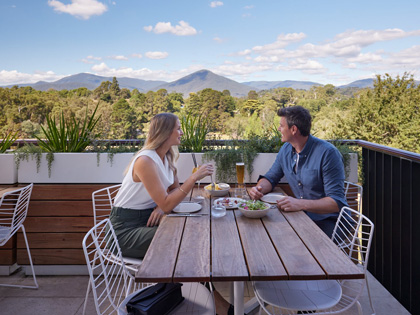 Couple dining on the blacony at Banyalla with stunning mountain views.