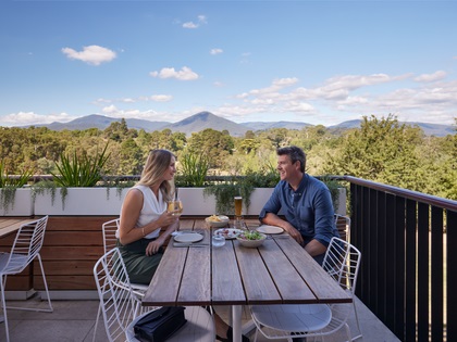 Couple enjoying a meal on an outdoor balcony.