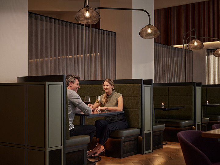 Two people sitting in a booth and drinking wine opposite each other at Banyalla, RACV Healesville Country Club and Resort.
