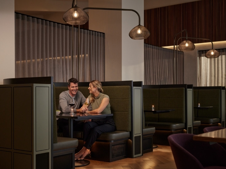 Two people sitting in a booth and drinking wine together at Banyalla, RACV Healesville Country Club and Resort.