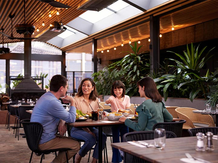 Parents and two children smiling together and eating at the Riddell's Green restaurant at RACV Healesville Country Club & Resort.