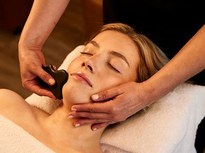Woman receiving a facial stone massage in a spa.